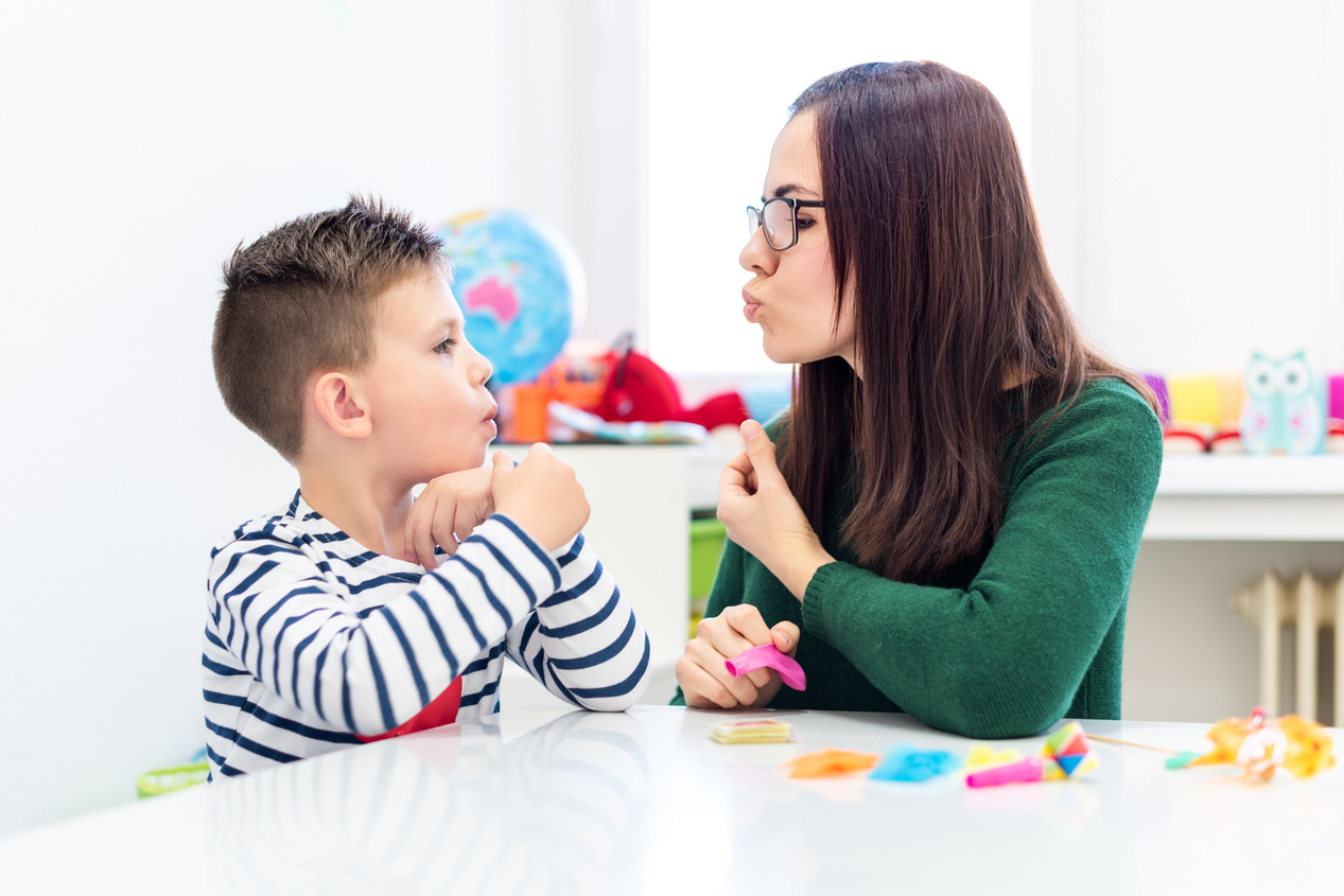 Children speech therapy concept. Preschooler practicing correct pronunciation with a female speech therapist.